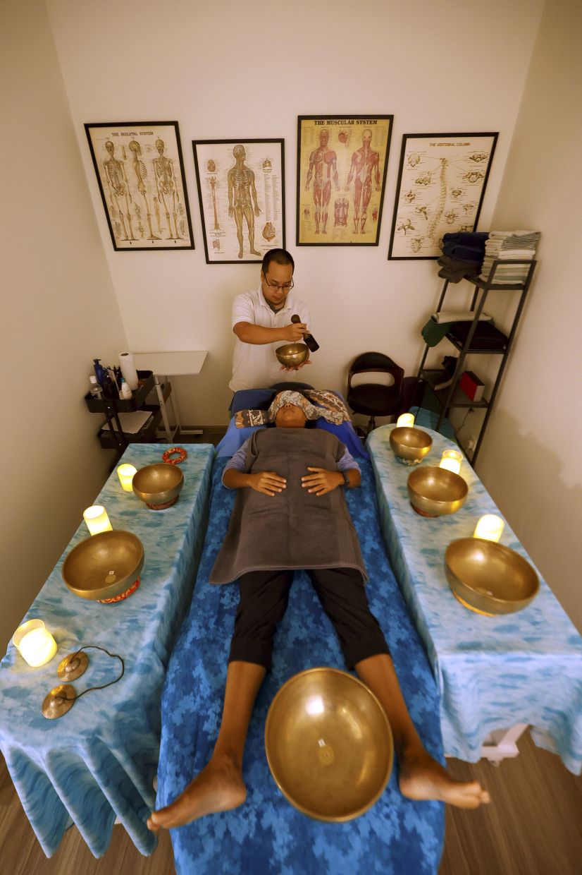 Sound healing therapist Daniel Iz'aan giving a one-to-one session to a client. Note how the seven singing bowls are placed.