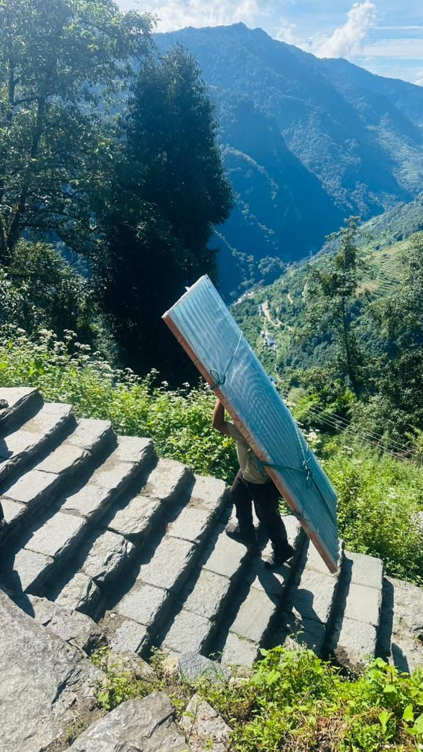 A porter carrying a solar panel walking upthe 12,000 steps at Jhindu Danda. 