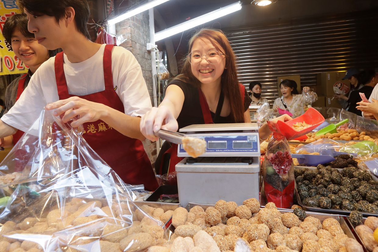 A saleswoman smiles to customers as they go shopping for the upcoming Chinese Lunar New Year celebrations at the Dihua Street market in Taipei, Taiwan, Sunday, Feb. 15, 202. -- AP Photo/Chiang Ying-ying