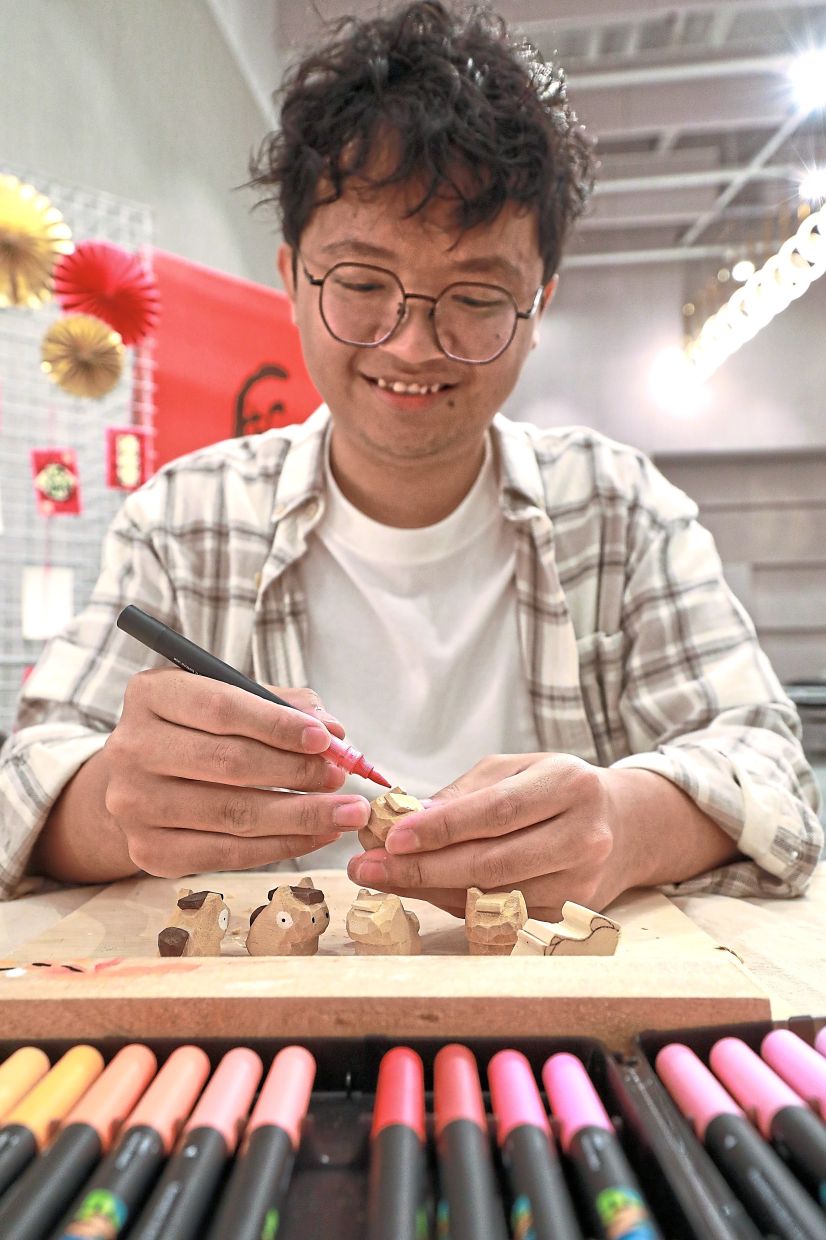 Lim using colour markers to sculpt his mini horses deftly carved out of wooden blocks.