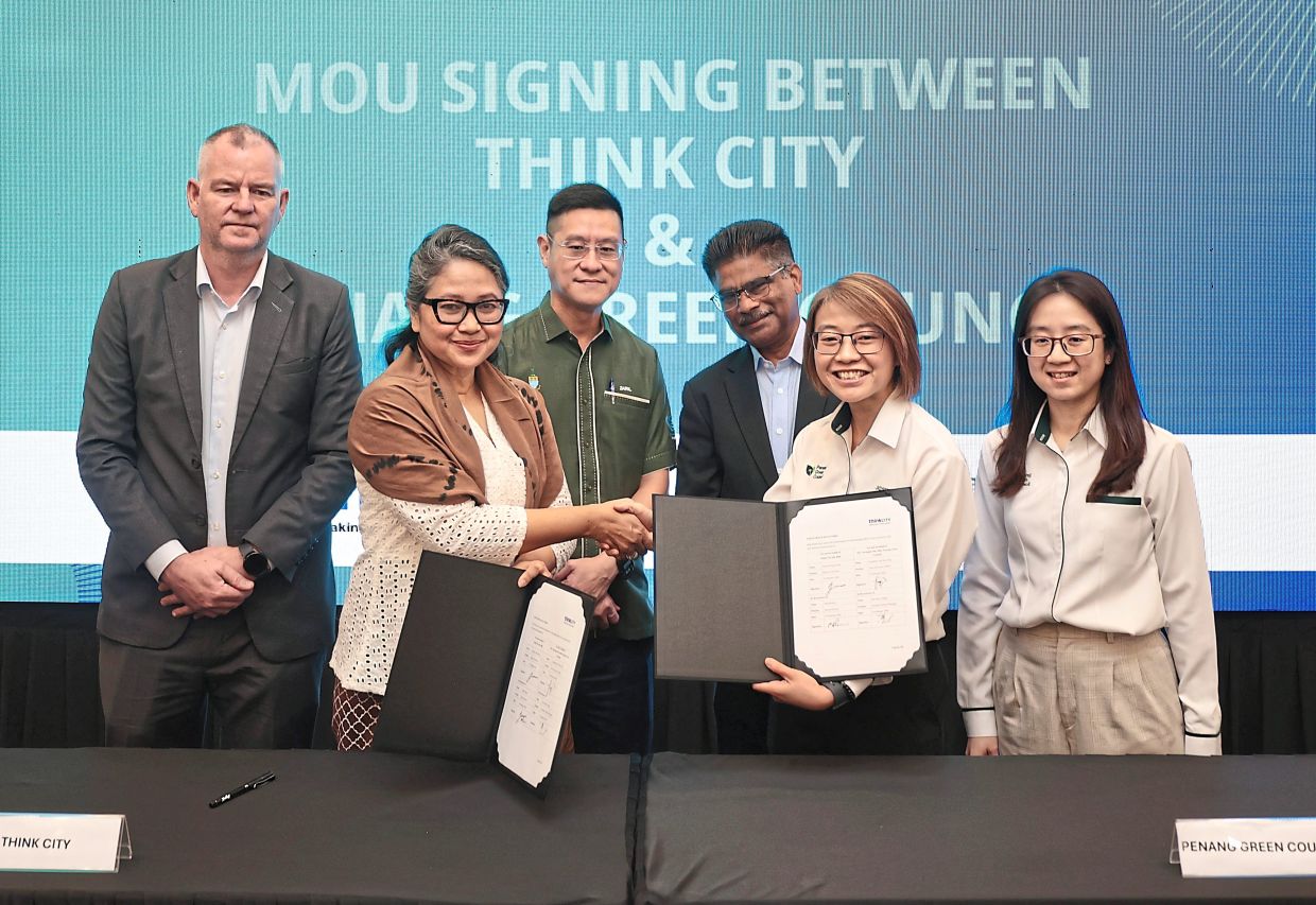 Suryani (front row, left) and Tan formalising the partnership programme witnessed by (back row, from left) Dr Benson, Zairil and Sundarajoo.