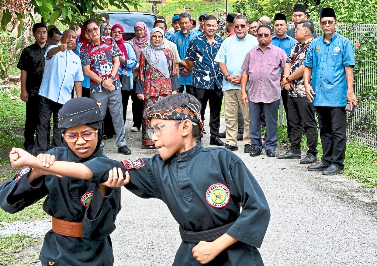 Steady moves: Azam (front row, second from left) watching a demonstration while officiating the Kampung Angkat Madani programme in Kampung Sungai Buah, Dengkil. — RAJA FAISAL HISHAN/The Star