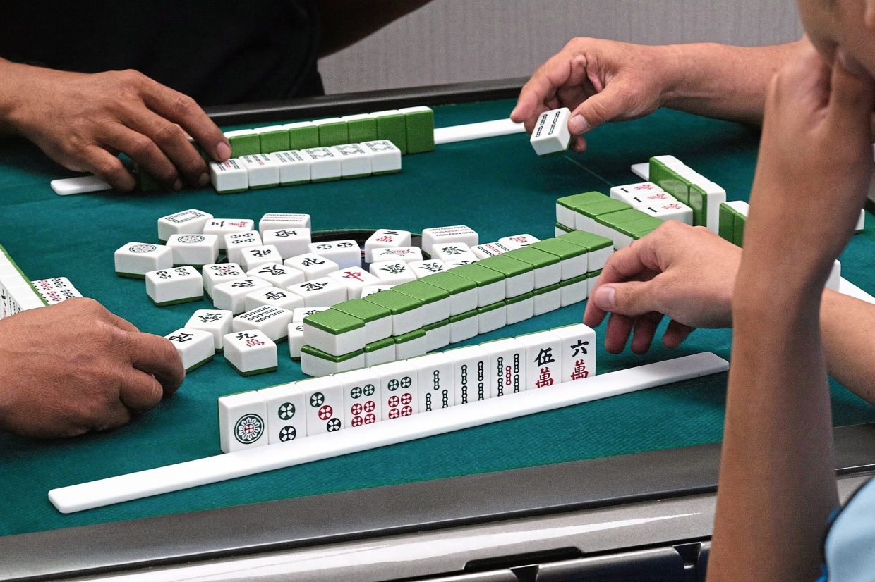 Playing mahjong promotes social ties. — Filepic