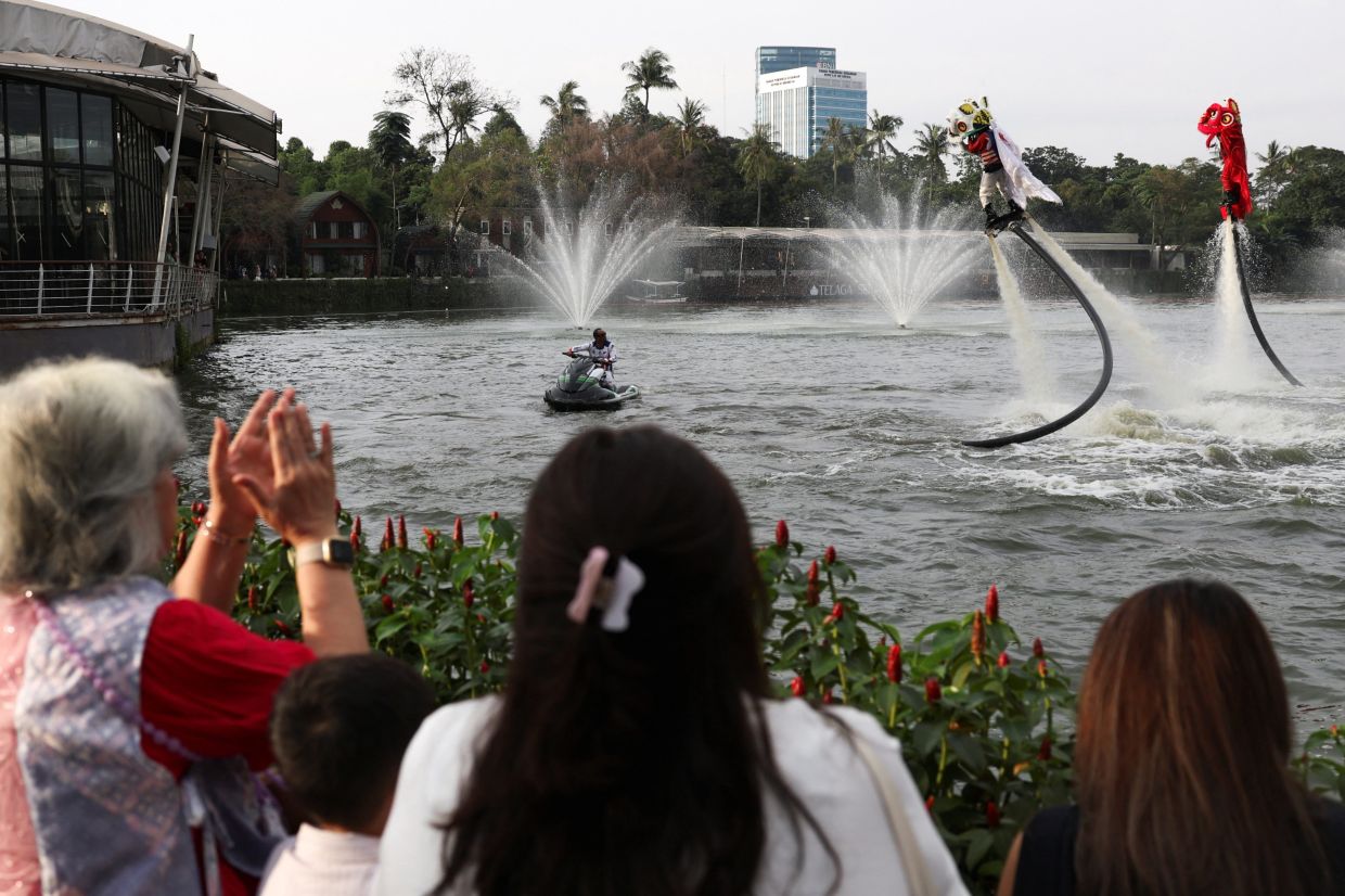 Spectators watch performers using flyboards to perform a lion dance at Senayan Park shopping mall ahead of the Chinese Lunar New Year, which will welcome the Year of the Horse, in Jakarta, Indonesia. -- REUTERS/Ajeng Dinar Ulfiana