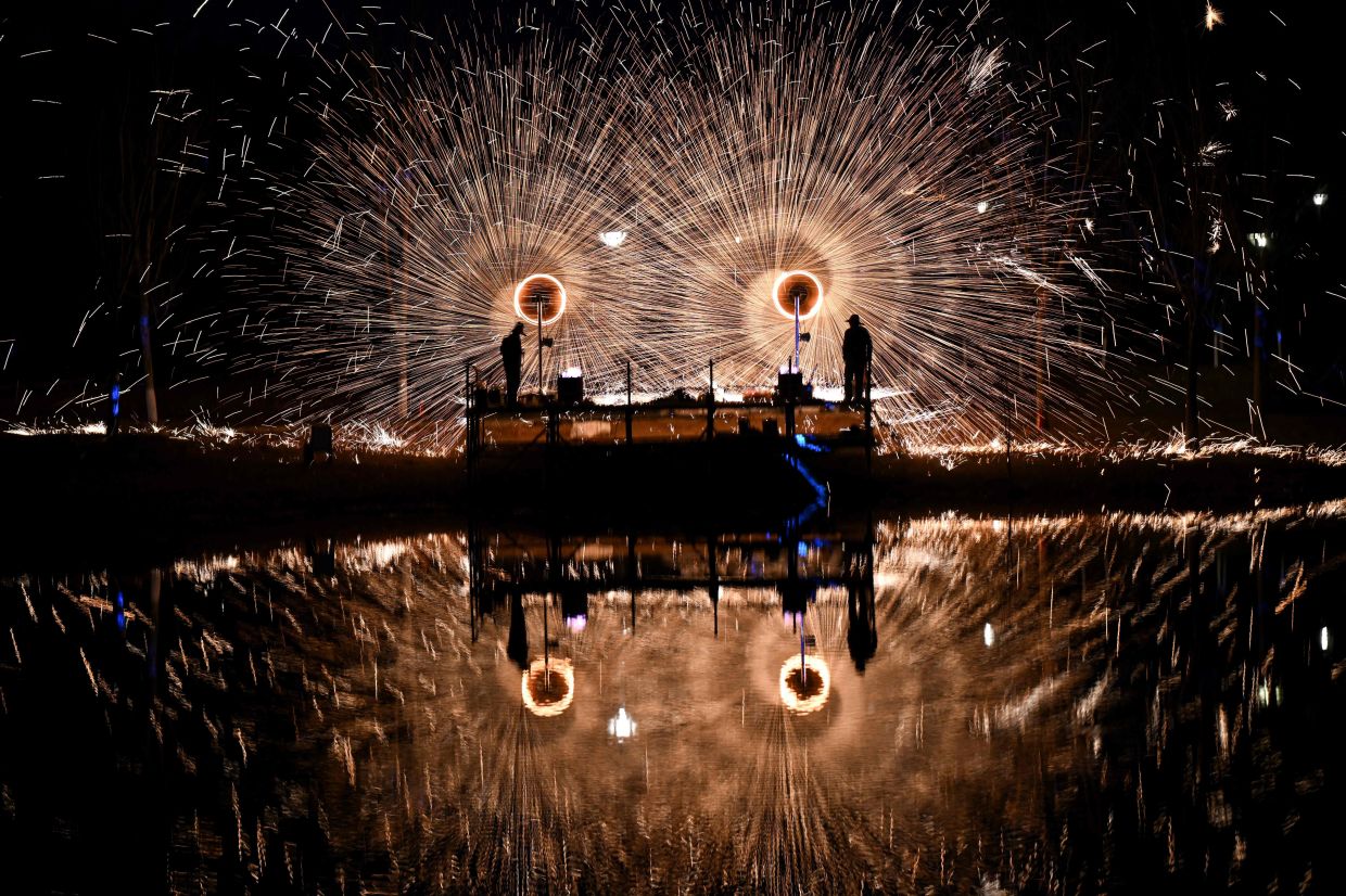 TOPSHOT - Men perform molten iron fireworks in a park in Beijing ahead of the Lunar New Year of the Horse. -- Photo by Pedro PARDO / AFP