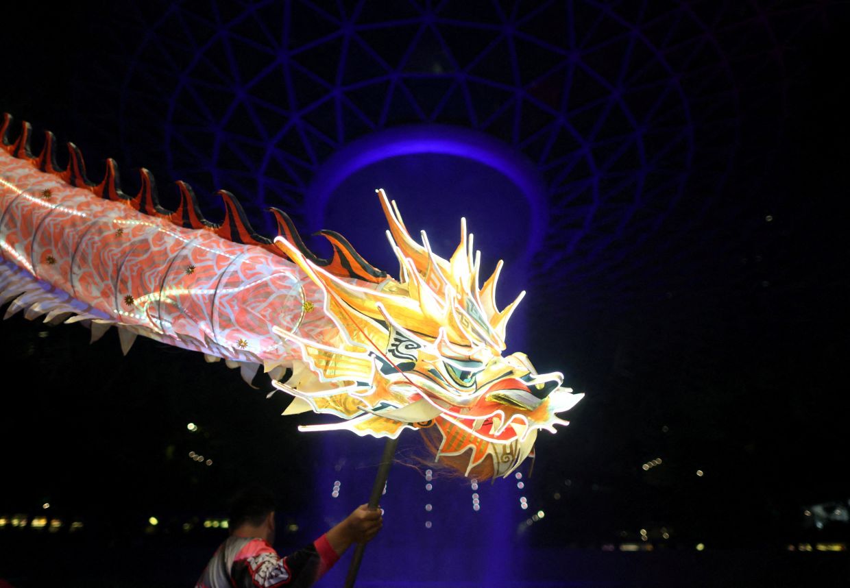 A dragon dance troupe performs an LED dragon dance on the eve of the Lunar New Year at Jewel Changi Airport in Singapore. -- Photo: REUTERS/Edgar Su
