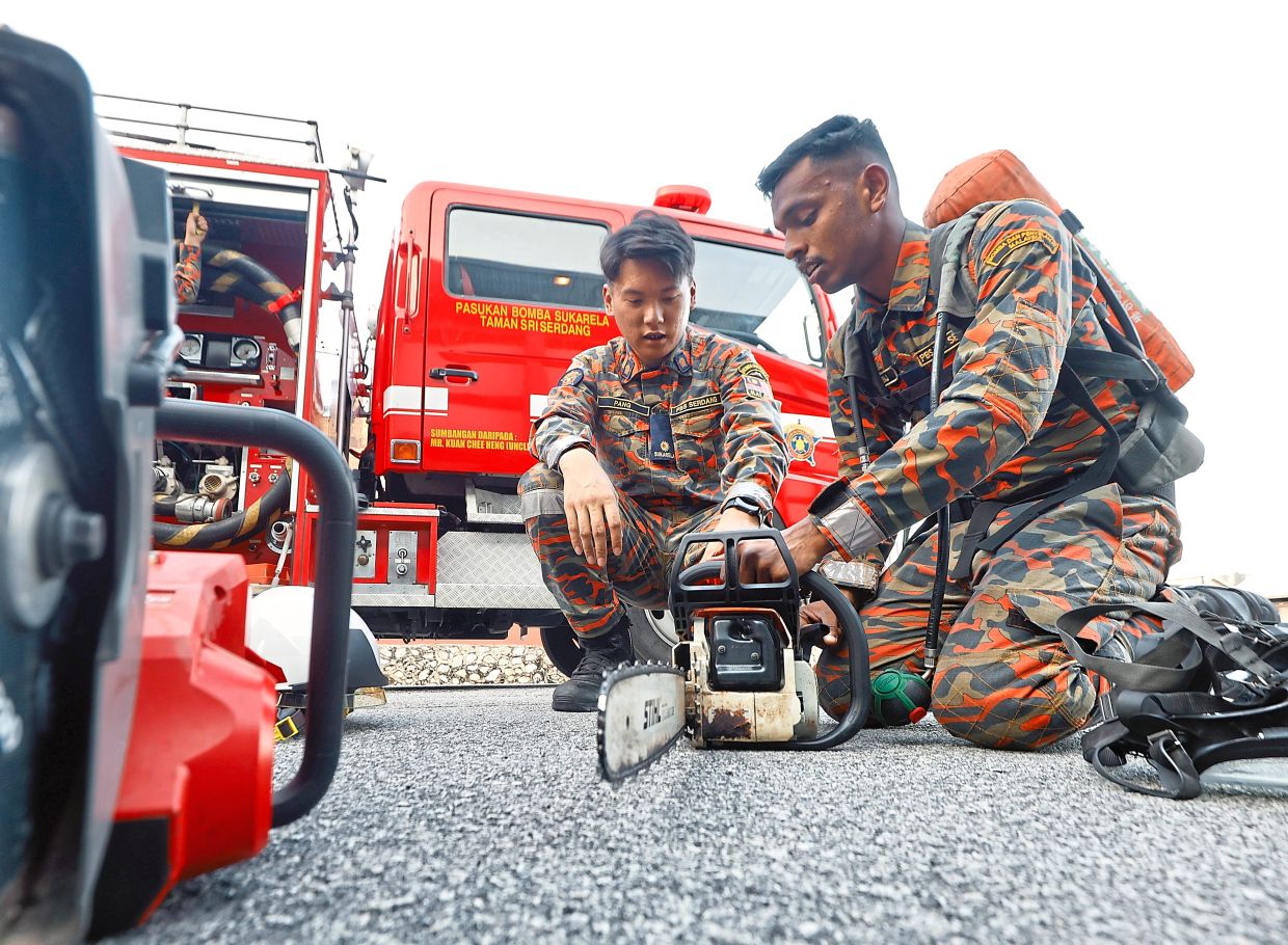 Taman Sri Serdang Volunteer Fire Department senior officer Scott Pang (left) and Jaganraj checking on the team’s equipment as part of their routine tasks.