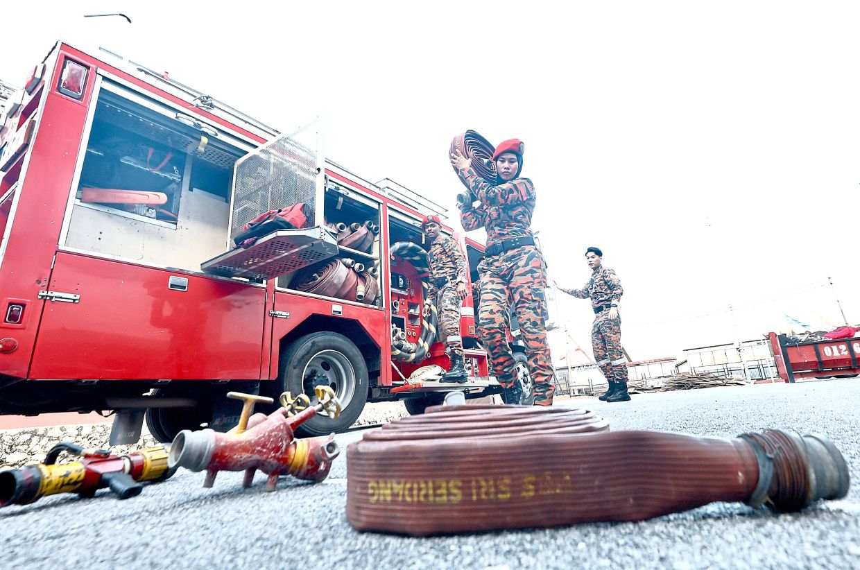 Siti Nurfitriah from PBS Serdang carrying a fire hose during an equipment inspection.