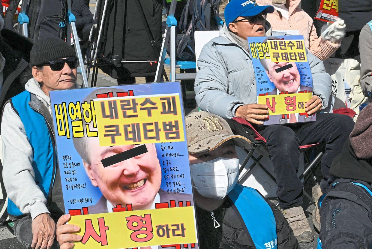 Protesters holding placards showing photos of Yoon with the words ‘A death sentence’ during a rally against the former leader ahead of his sentencing. — AFP 