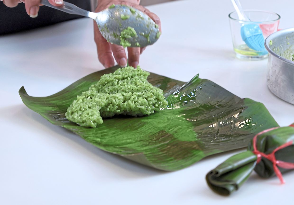 Place the cooked rice at narrow end of the wilted banana leaf.