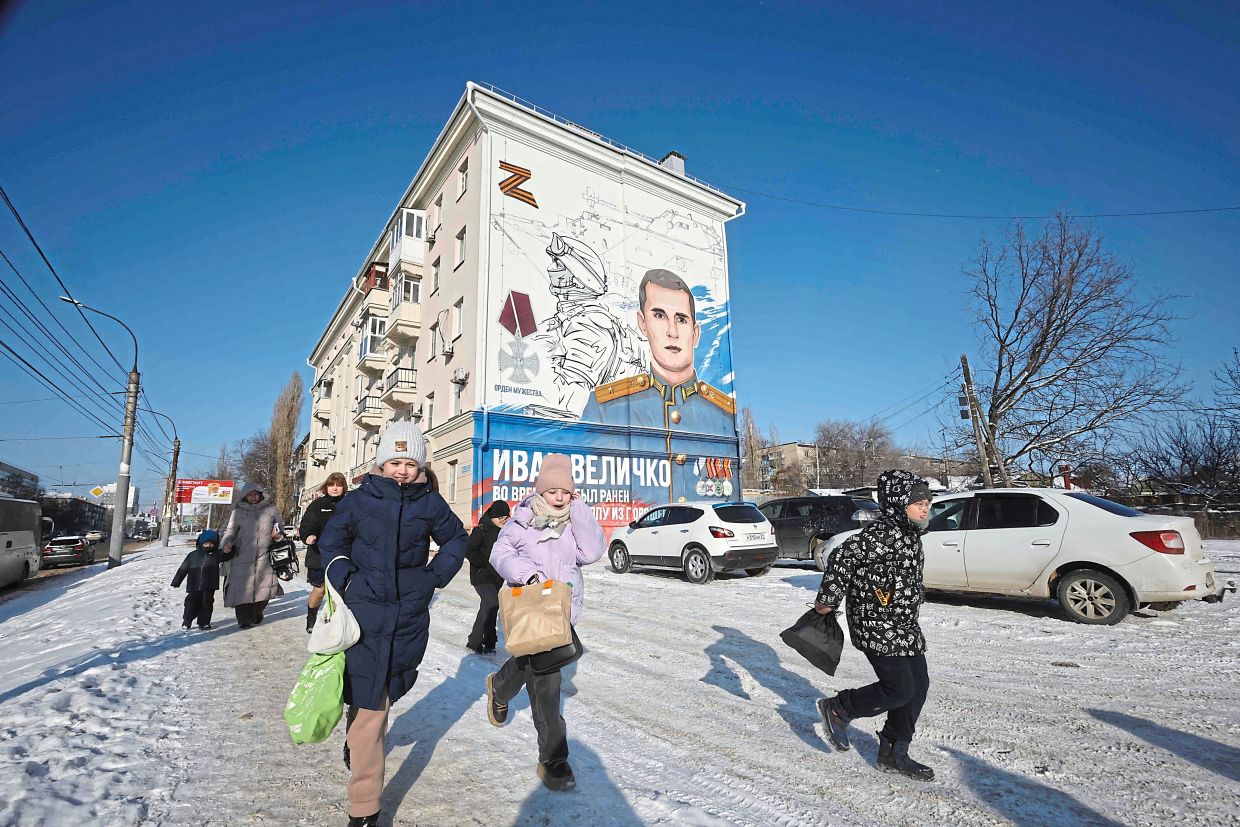 Children running in front of a residential building decorated with a mural depicting a Russian soldier who died fighting in Ukraine, in Voronezh. — AFP