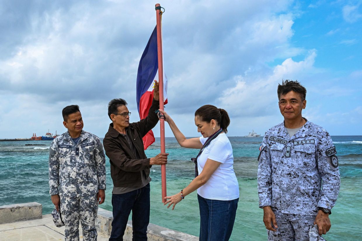 (L-R) Commodore Jay Tarriela, spokesperson of the Philippine Coast Guard for the South China Sea, Municipal Mayor Beltzesar Alindogan of Kalayaan, Philippine Senator Risa Hontiveros, and Acting Commander of Western Command Commodore Charles Merric Villanueva raise a Philippine flag on Thitu Island in the South China Sea on Saturday, February 21, 2026. A Philippine senator called for deepening defence relationships and continuous pushback against China's claims in the South China Sea while visiting one of Manila's tiny possessions in the disputed waterway on February 21. -- Photo by Jam STA ROSA / AFP