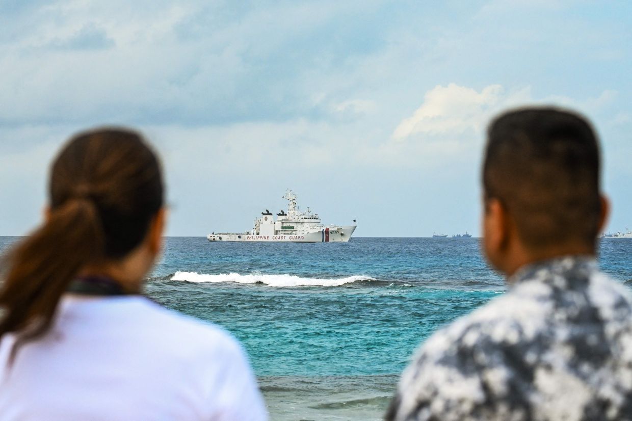 Philippine Senator Risa Hontiveros (left) and Commodore Jay Tarriela, spokesperson of the Philippine Coast Guard for the South China Sea, look at a Philippine Coast Guard ship from Thitu Island in the South China Sea on February 21, 2026. A Philippine senator called for deepening defence relationships and continuous pushback against China's claims in the South China Sea while visiting one of Manila's tiny possessions in the disputed waterway on February 21. -- Photo by Jam STA ROSA / AFP