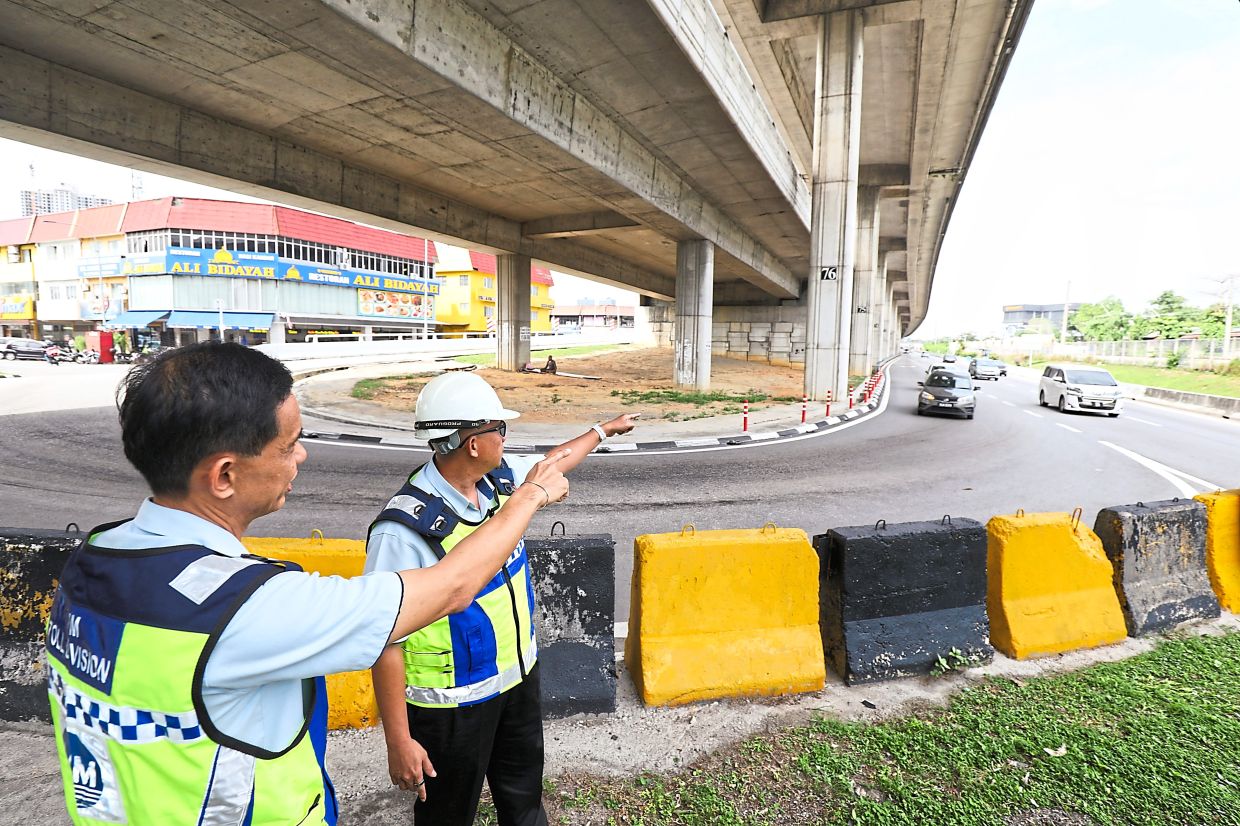 Ong (left) inspecting the flood-prone stretch at KM18.9 near Taman Maju Jaya with a fellow employee. — Courtesy photo