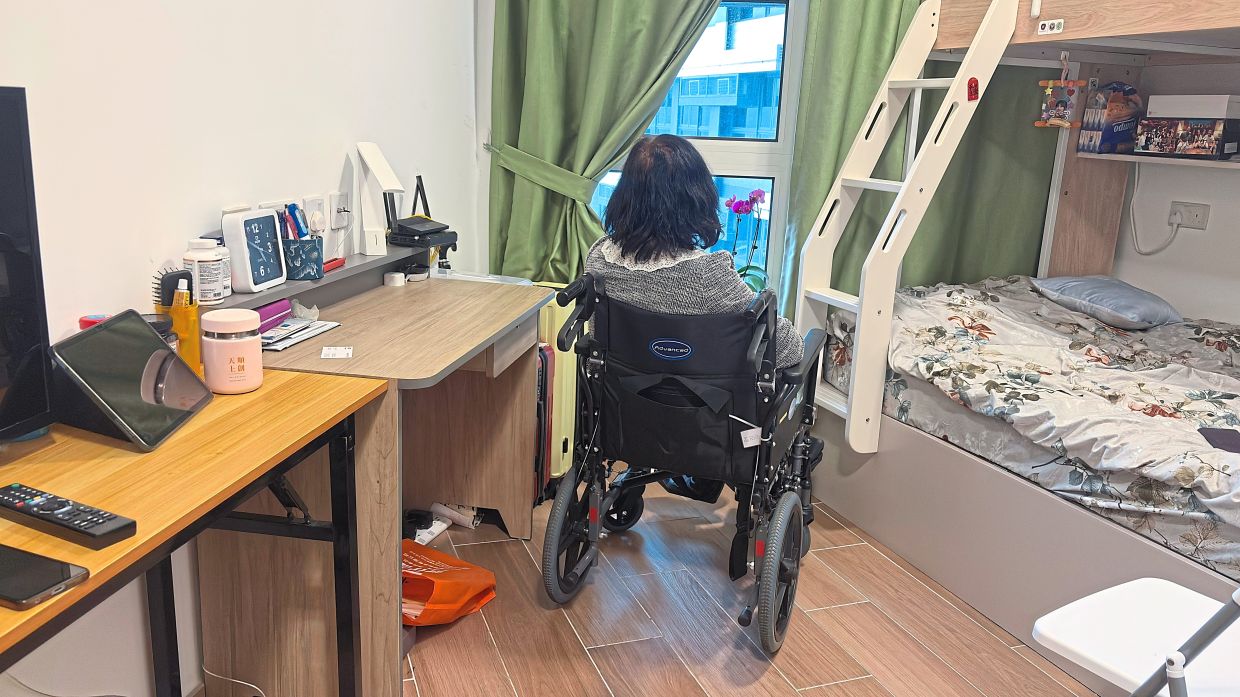Chan gazing out of a window at her temporary housing unit at a youth hostel. — AP