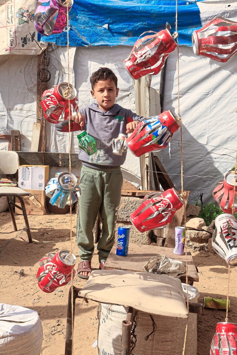 A Palestinian child stands near handmade Ramadan lantern decorations crafted from recycled materials in Khan Younis in the southern Gaza Strip. Photo: Reuters 