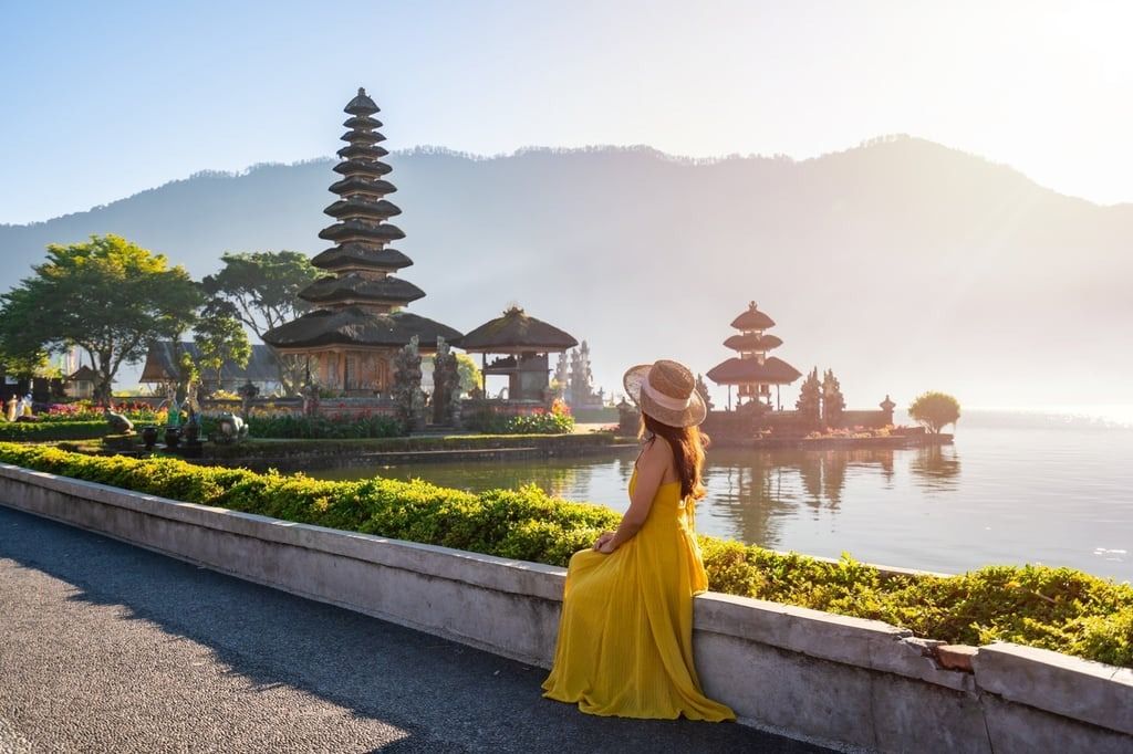 A young woman tourist relaxing and enjoying the beautiful view at Ulun Danu Beratan temple in Bali. -- Photo: Shutterstock
