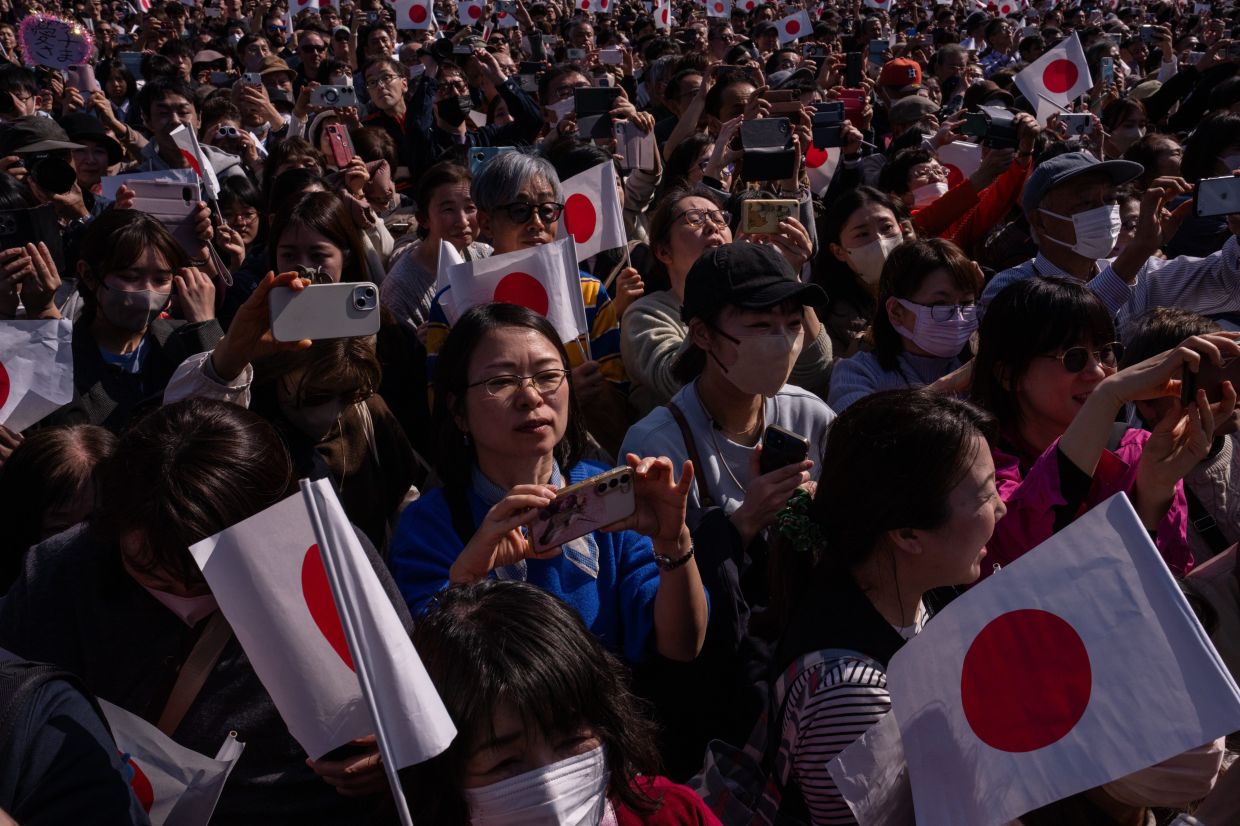 Well-wishers wave flags at Japan's Emperor Naruhito and other members of the imperial family during a public appearance marking the emperor's 66th birthday at the Imperial Palace in Tokyo, Monday, Feb. 23, 2026. -- AP Photo/Louise Delmotte