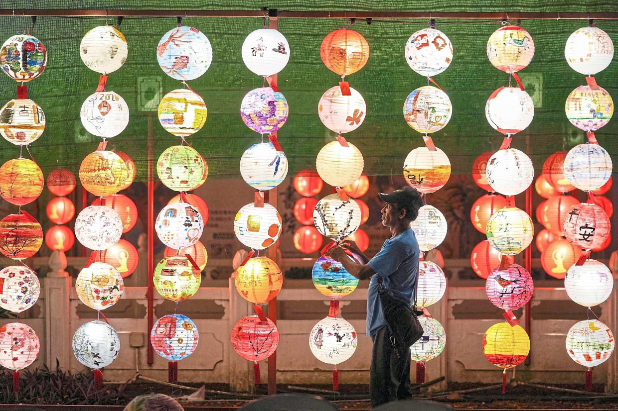 TOPSHOT - A worker hangs illuminated lanterns during the Lanterns and Flora Festival at the Fo Guang Shan Dong Zen Temple ahead of the upcoming Lunar New Year of the Horse in Jenjarom, Malaysia's Selangor state on February 10, 2026. (Photo by Arif Kartono / AFP)