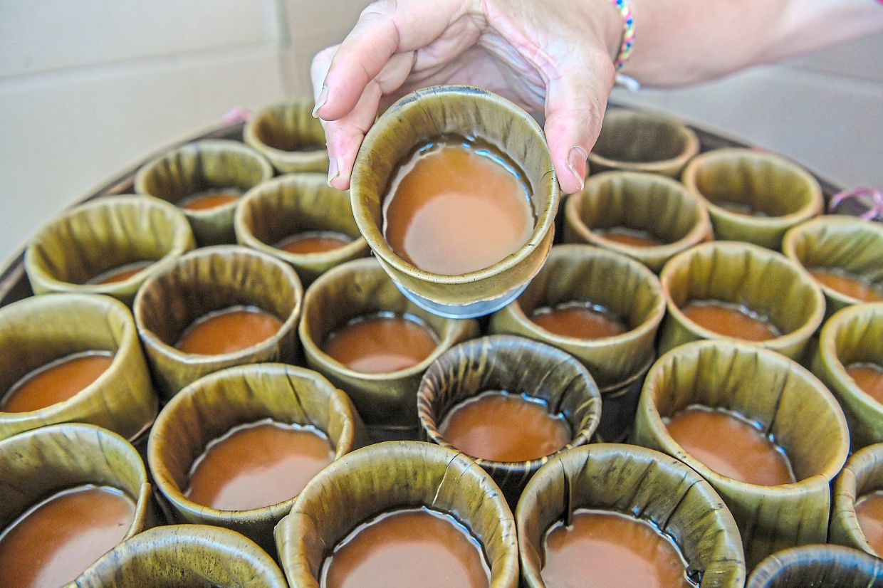 Freshly steamed kuih bakulwrapped in banana leaf moulds, showing the smooth, glossy surface achieved after 24 hours of steaming.