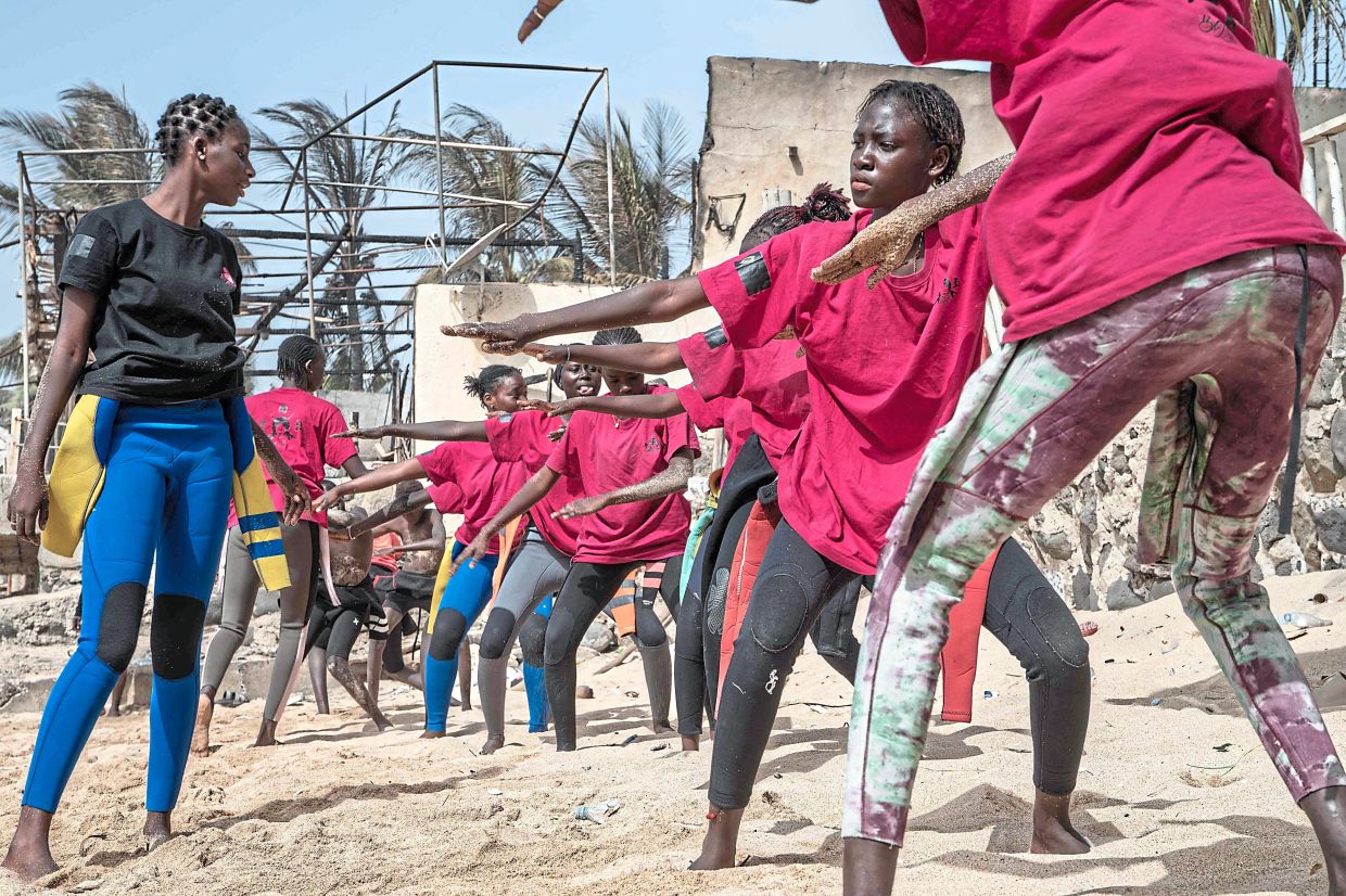 Soukeye (in black) coaching a dozen young Senegalese girls at the beach. About 20 participants from Xataxely – a tight-knit fishing village within the capital’s Ngor neighbourhood – are part of an inaugural Surf Academy that requires them to attend school, with the promise of riding waves serving as the incentive. — AFP