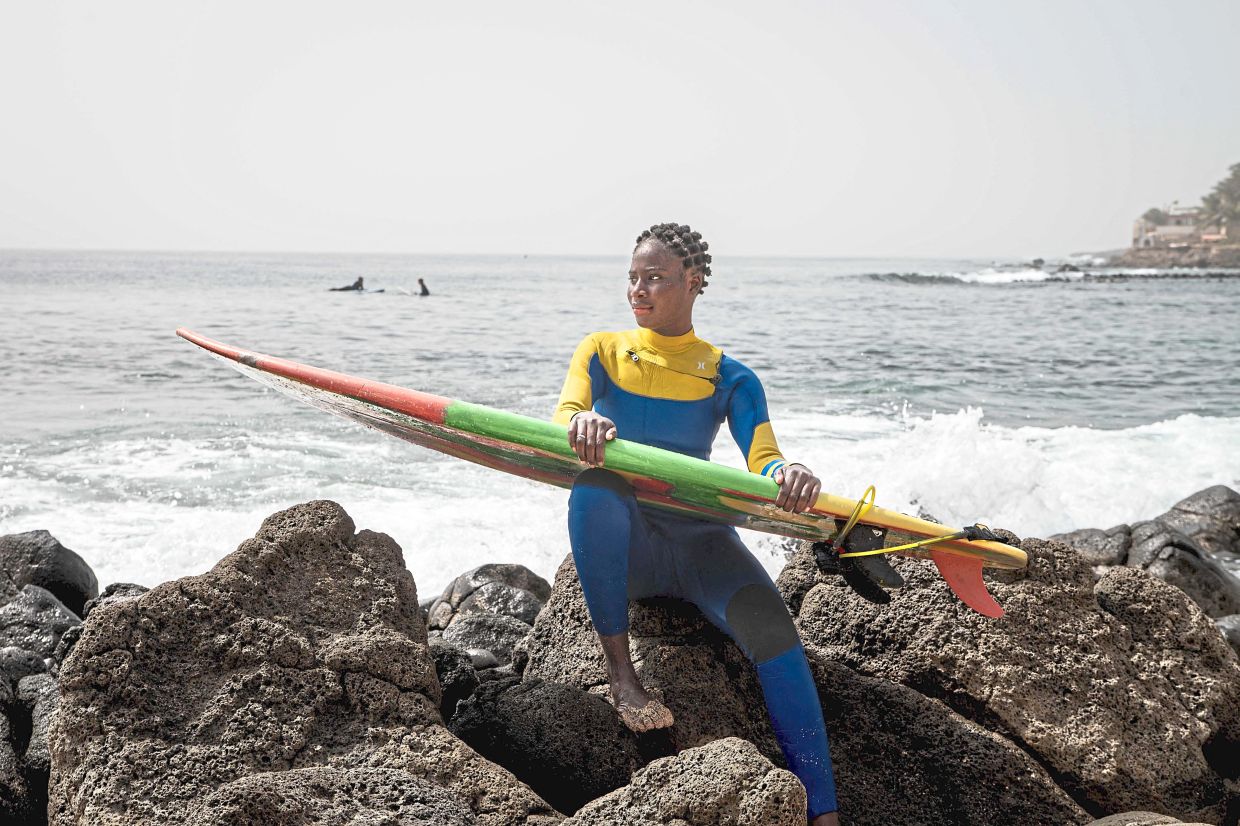 Soukeye posing with her surfboard on a beach on the Almadies coastline in Dakar. Soukeye has been taking part in Surf Academy since 2019 and is responsible for training new participants. — AFP