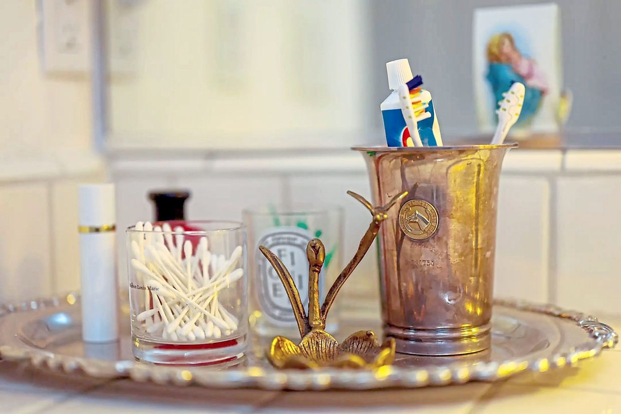 In the bathroom, a mint julep cup that was given as a trophy at the 1964 Peacock Hill National Horse show holds toothpaste and toothbrushes. 