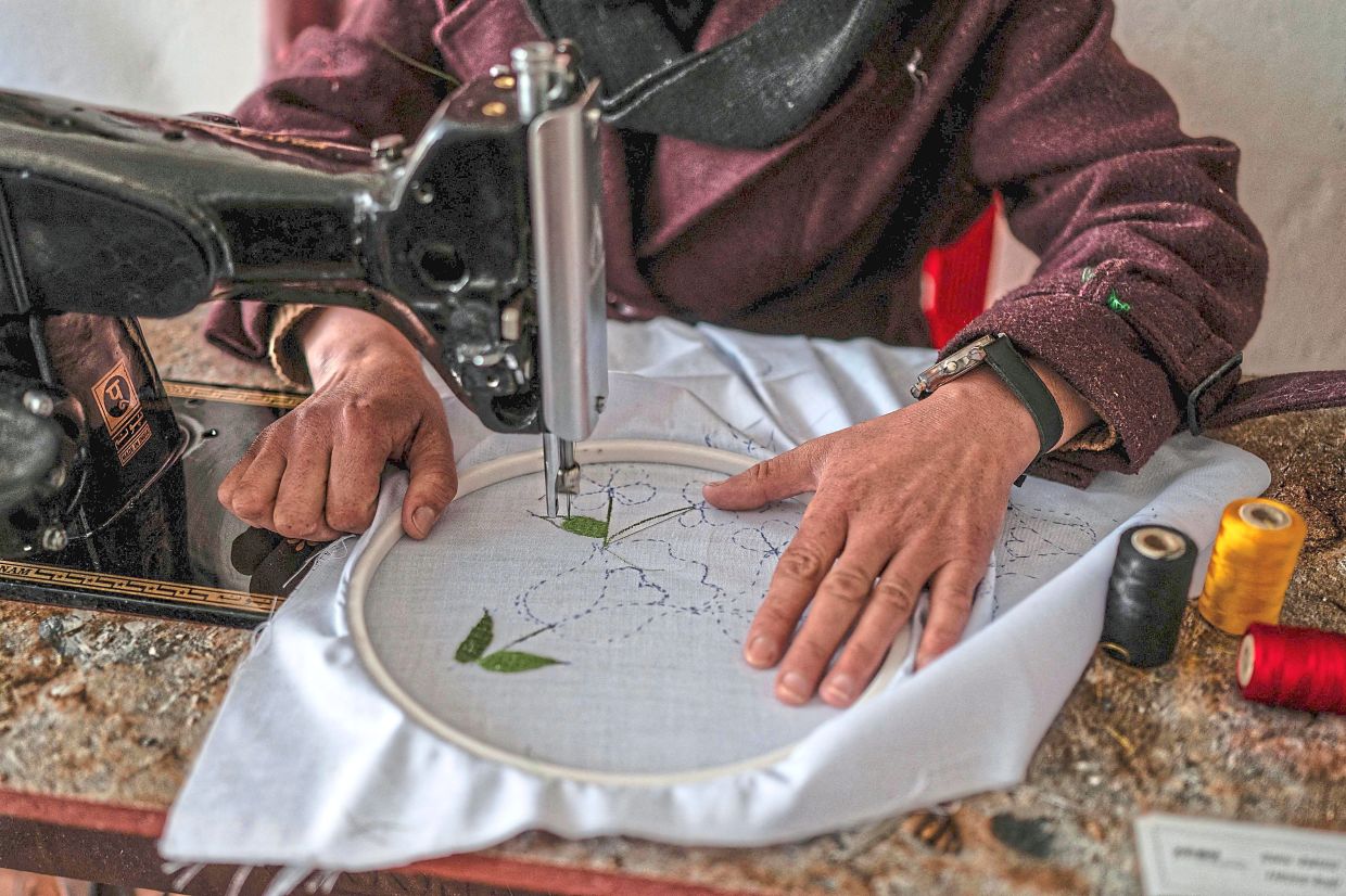 Rahima embroidering a scarf at her boutique.