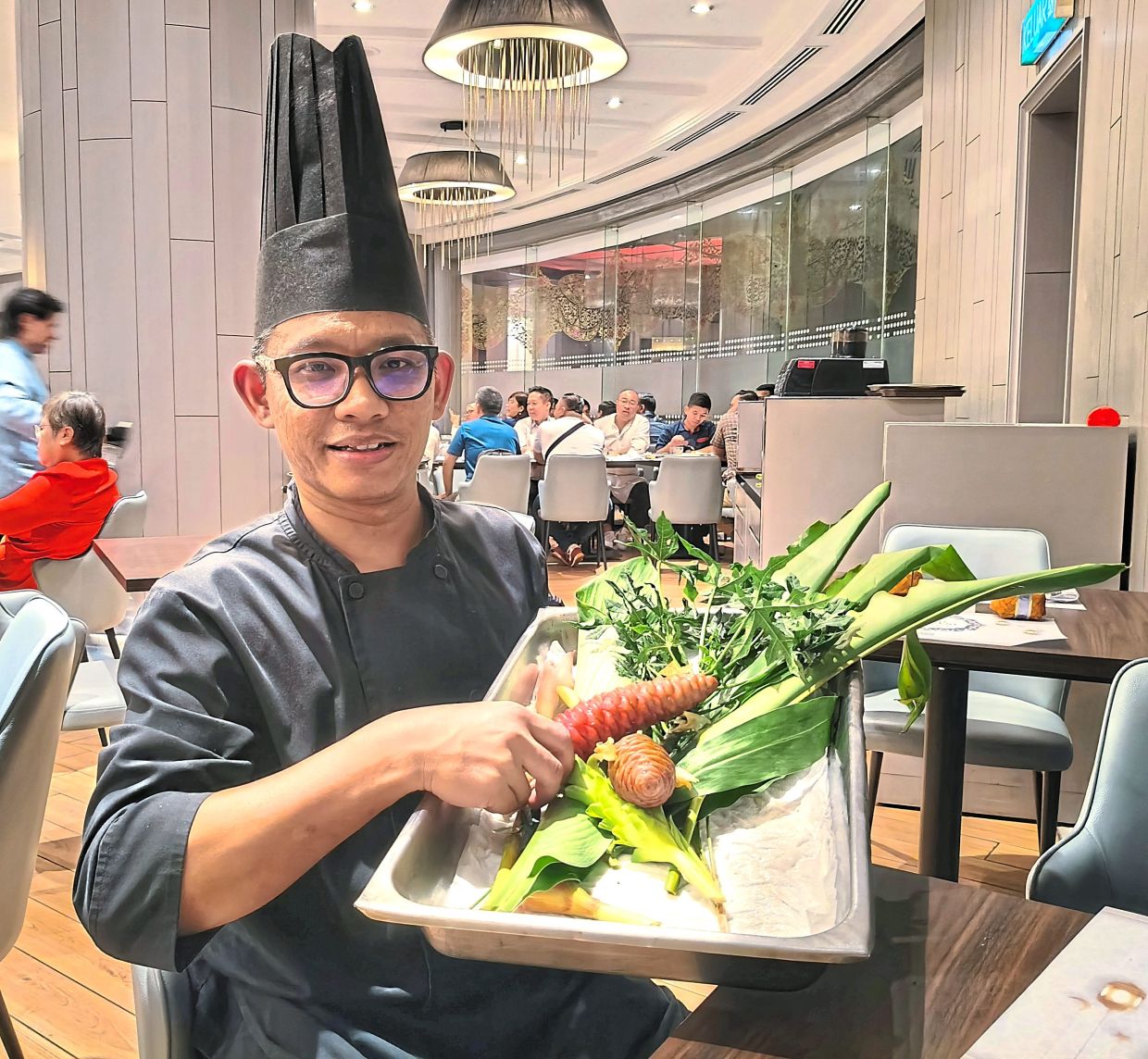 Sous chef Adzlan showing the ‘daun cahya’, ‘bunga lempoyang’ and other ‘ulam’ he uses to make ‘botok-botok’. 