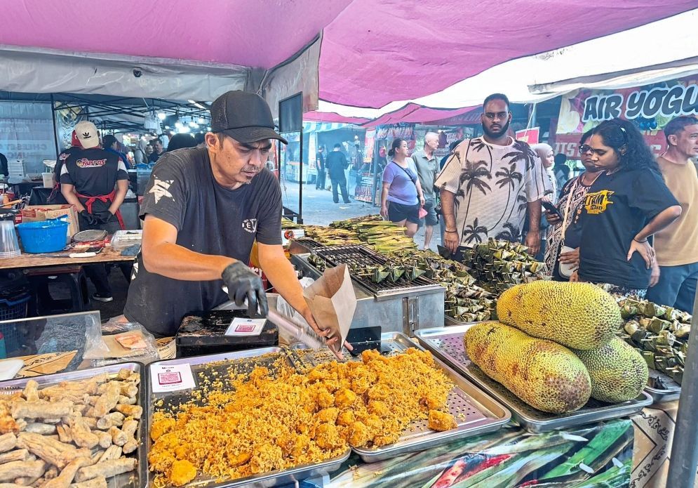 Crispy delight: A ‘cempedak goreng’ seller attending to customers at Taman Perling Ramadan Bazaar in Iskandar Puteri, Johor. Local food traders are reporting improved sales this fasting month. — MOHD FARHAAN SHAH/The Star