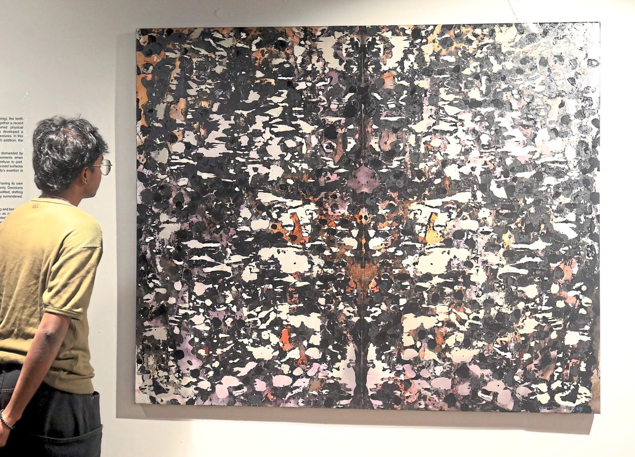 A gallerist views artist Hamidi’s new abstract work from his 10th solo exhibition, 'Tracing Stillness (Menjejak Hening)', at Wei-Ling Gallery. Photo: The Star/Azlina Abdullah 