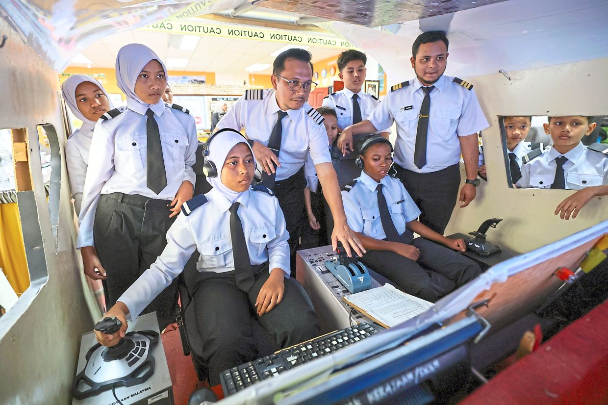 SK Gong Nangka senior assistant of student affairs Syed Hasan Syukri (standing centre) guiding pupils in a flight simulation exercise.