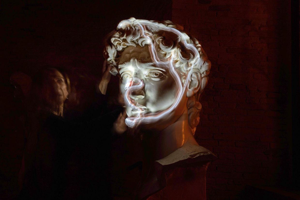 Terre uses a small light on her fingers while touching a life-size reproduction of the head of Michelangelo’s David as she poses for a long-exposure photograph at the Omero Tactile Museum in Ancona, Italy. Photo: AP