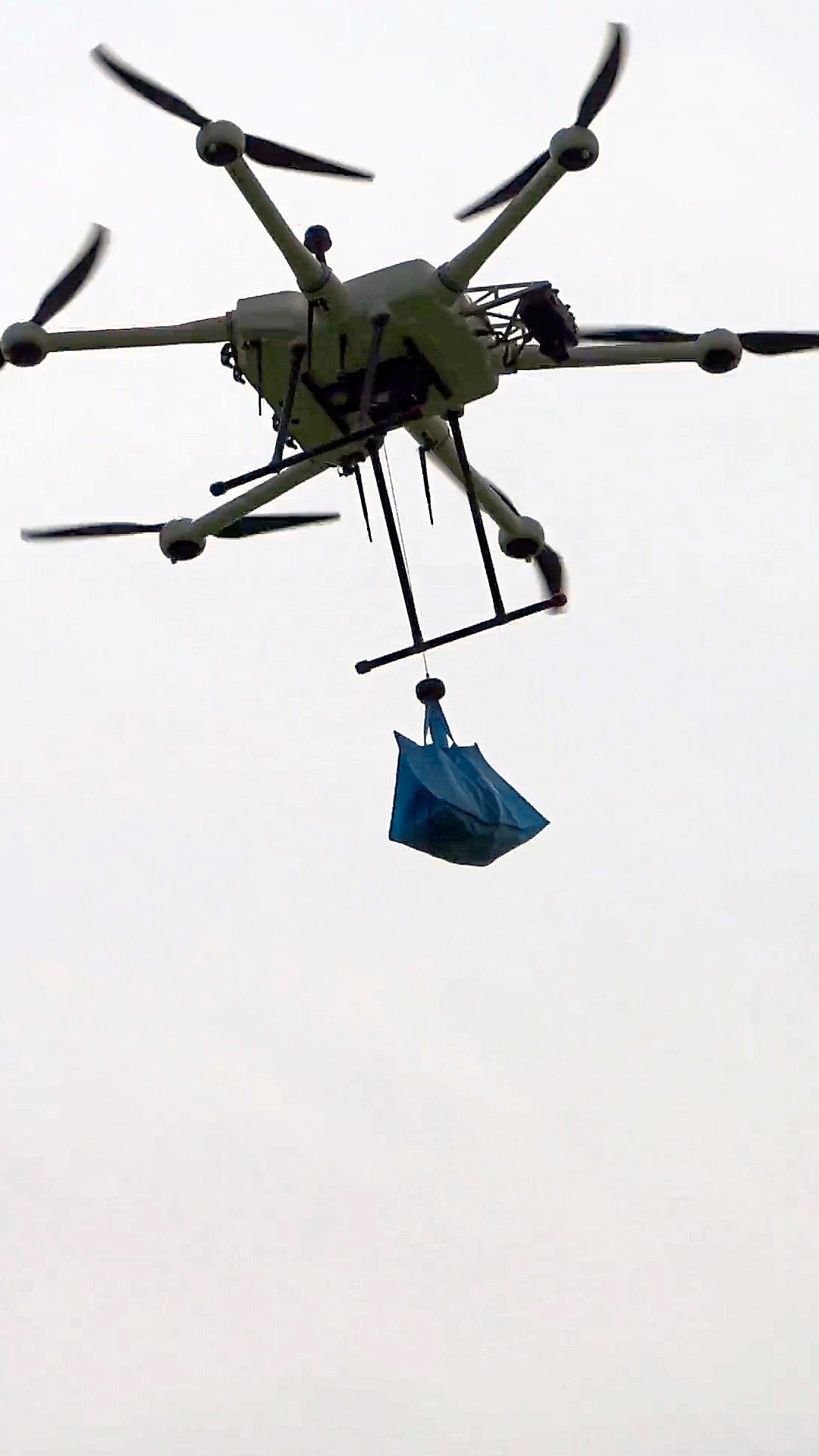 A lunch order is lowered by cable from an aerial delivery drone.