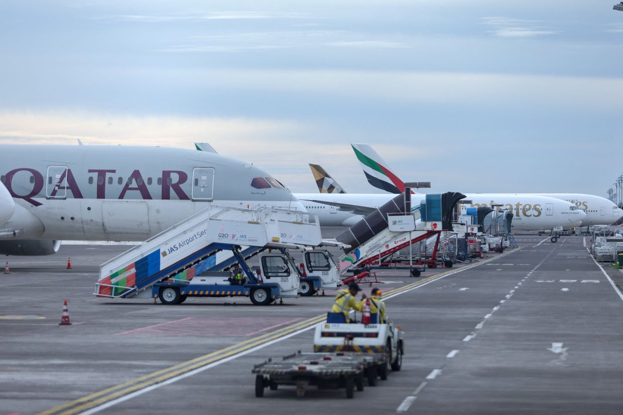 Qatar Airways and Emirates Airways plane is parked at I Gusti Ngurah Rai International Airport as some flights to Dubai and Doha cancelled following strikes on Iran launched by the United States and Israel, in Kuta, Bali, Indonesia, on Sunday, March 1, 2026. -- Photo: REUTERS/Johannes Christo