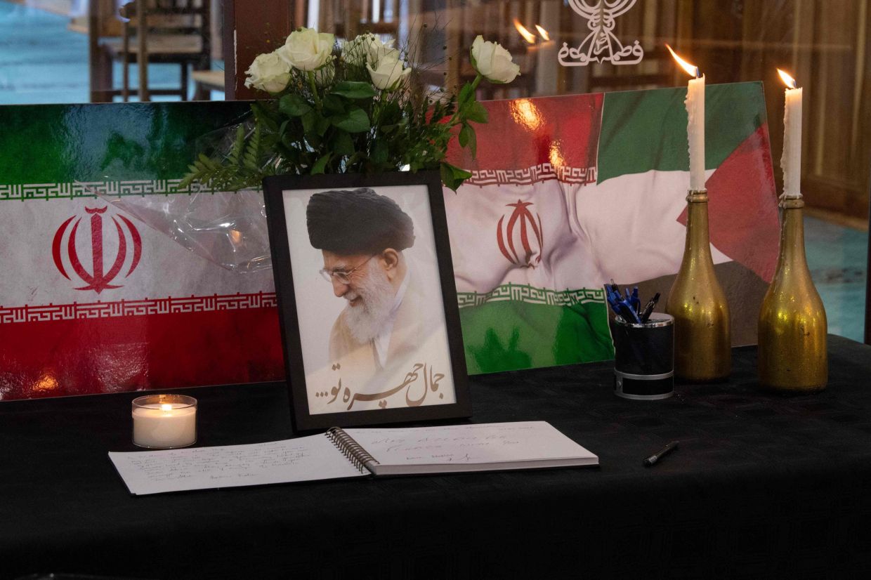 A portrait of Iran's Supreme Leader Ayatollah Ali Khamenei is displayed next to Iranian flags, candles, and a book of condolences at the Ahlul Bait Mosque Complex, while Muslim worshippers pray in his memory in Cape Town on March 01, 2026. Ayatollah Ali Khamenei, Iran's supreme leader since 1989 and sworn enemy of the West, was killed in the opening salvo of a massive US and Israeli attack, sparking a new wave of retaliatory missile strikes from Tehran on Sunday, March 1, 2026. -- Photo by RODGER BOSCH / AFP