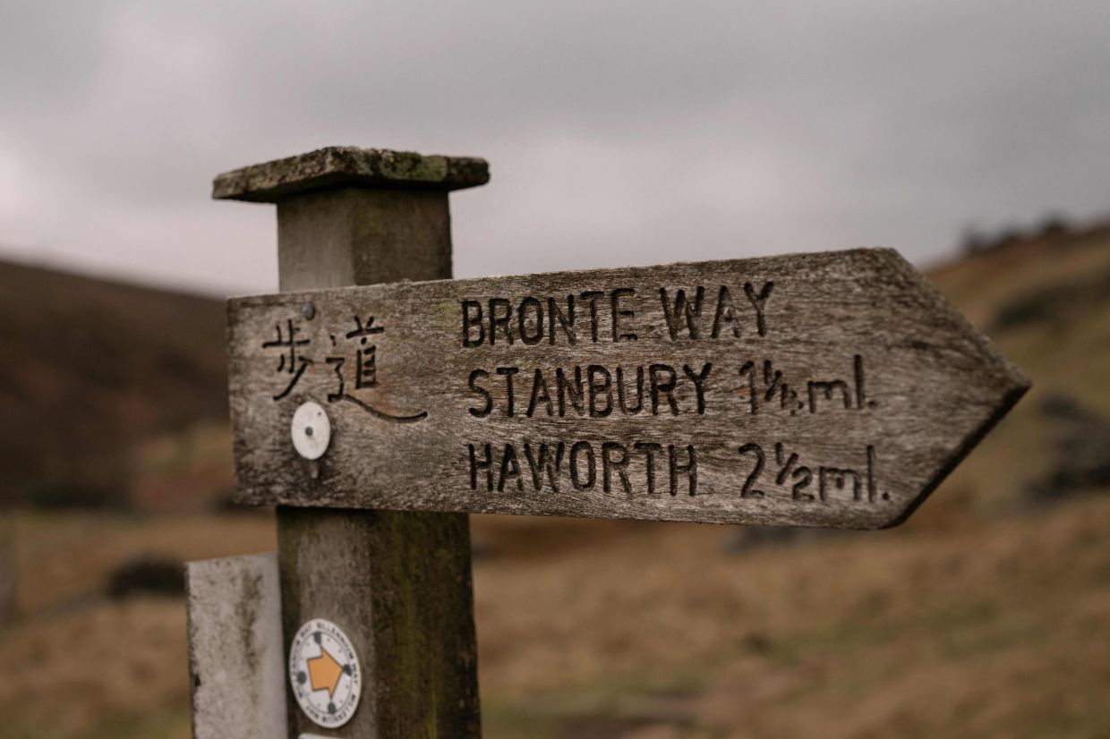 A footpath sign marking the direction of the Bronte Way includes a notice in Japanese due to the number of tourists visiting the site, near Haworth, northern England. Photo: AFP