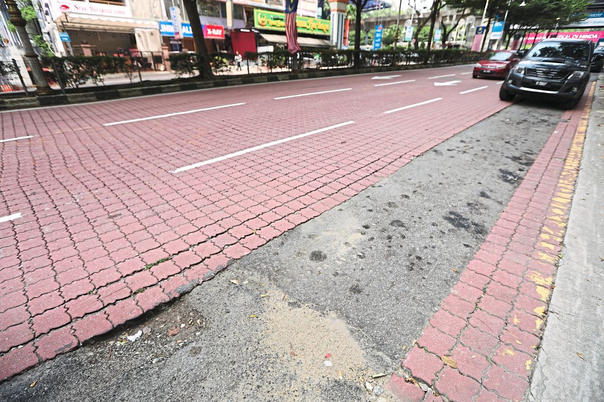 An asphalt strip replaces interlocking brick paving along a stretch in Little India, Brickfields, leaving an uneven surface and raising concerns over poor reinstatement following utility works in the heritage area.