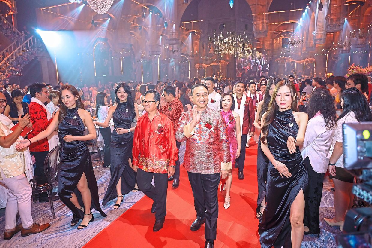 Mita (right, waving) accompanying Chua as they walk into the hall for the event.