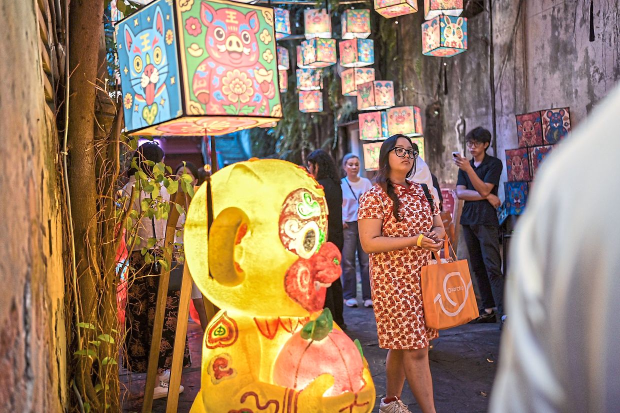 A visitor in a ‘cheongsam’ walks by an illuminated monkey figure, one of the 12 animal zodiac signs.