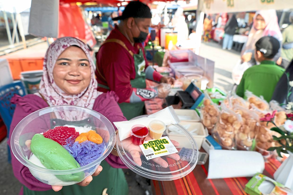 Nurfathmi and Mohd Shazwan (in the background) selling Es Pisang Ijo, originally from Indodesia, at Bandar Putra Bertam Ramadan bazaar. 
