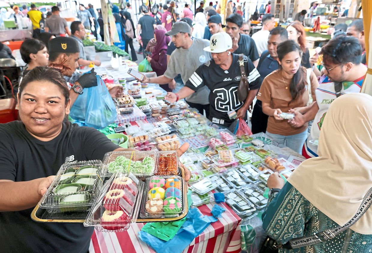 Aisyah (left) sells around 50 types of local kuih and desserts at Prangin Mall Ramadan bazaar. 