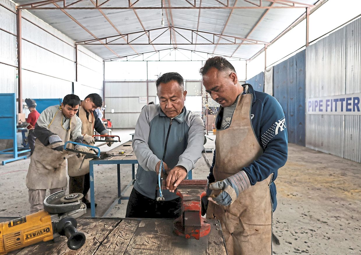 How it’s done: A trainer instructing a man on the tools of the trade in construction work. — Reuters