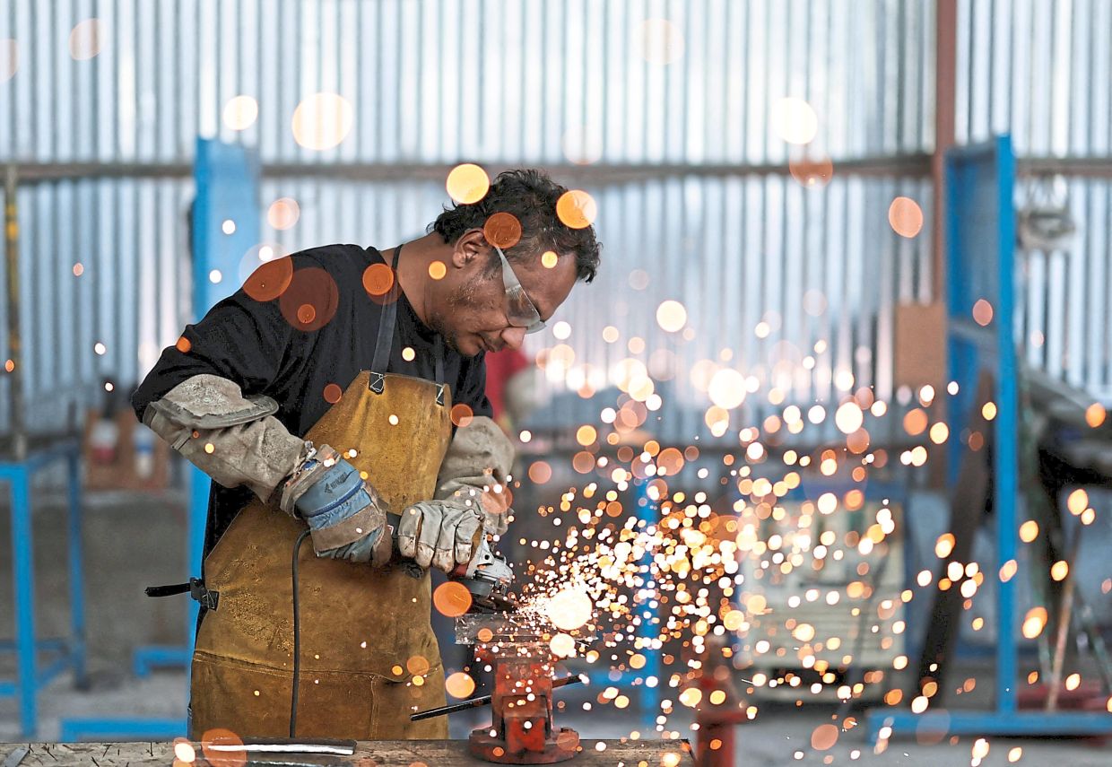 Learning the job: Steve Shrestha, 36, who is planning to leave the country and apply for foreign employment, grinding a piece of metal as he learns to weld at Motherland Overseas, a recruitment agency in Kathmandu. — Reuters
