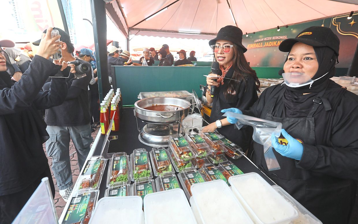 DJ Elly (left) hyping up Noradila as she sells her ‘Ikan Sambal Harum Manis’ at the bazaar in Shah Alam.