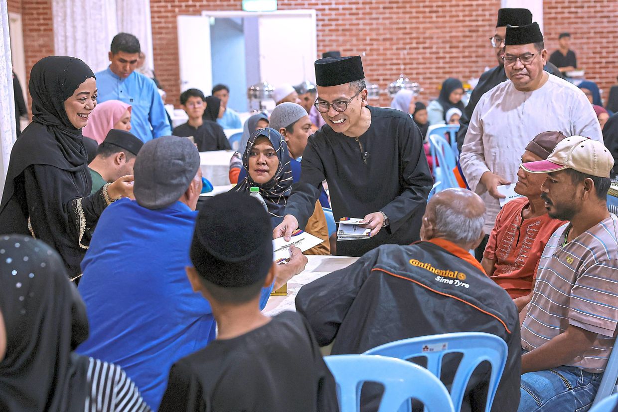 The spirit of the season: Fahmi handing out donations to recipients from table to table at a buka puasa event at the Al-Khadijah Mosque in Pantai Dalam. — Bernama