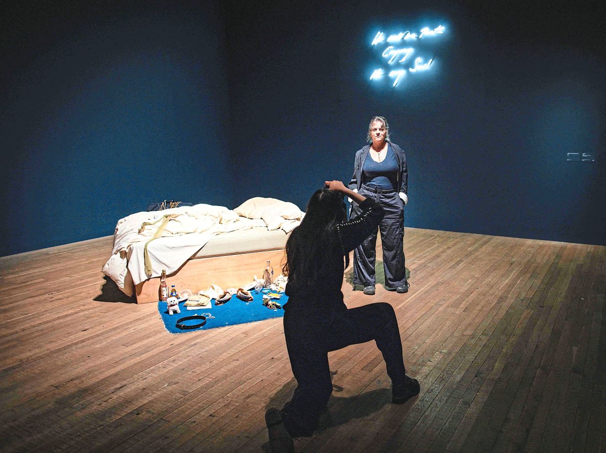 Emin being photographed beside her artwork 'My Bed' during a preview of her show at the Tate Modern in London. Photo: AFP 