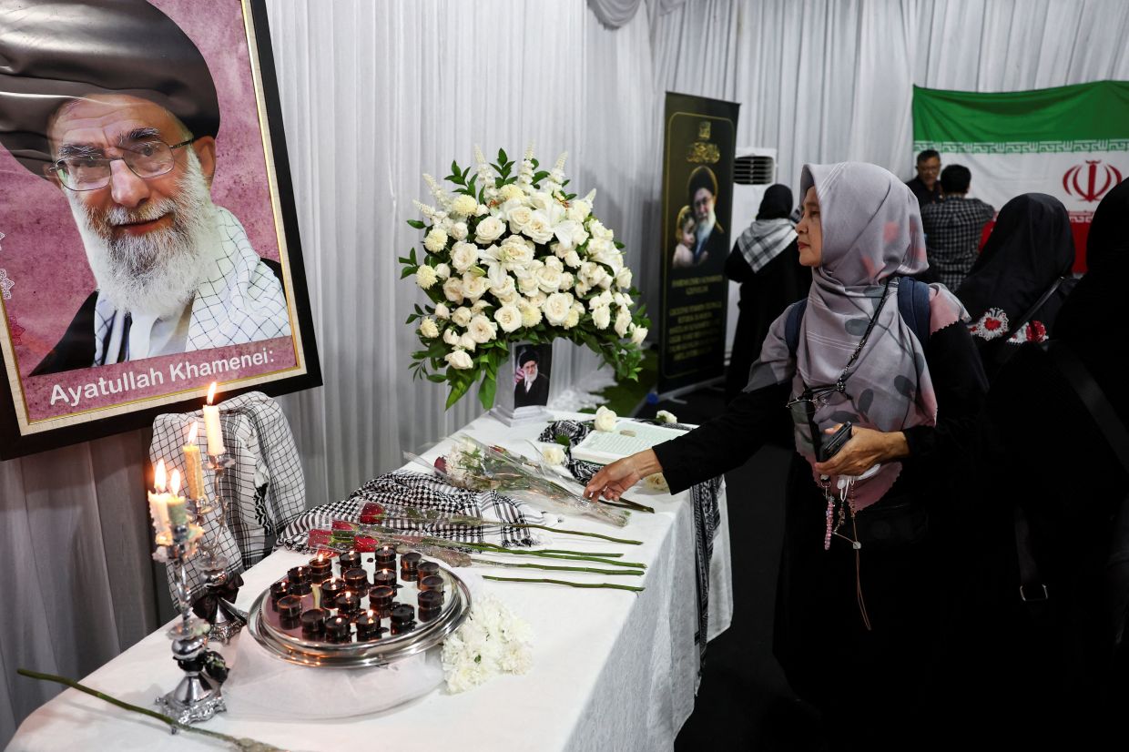A Muslim woman placing flowers before a picture of Iran's late Supreme Leader Ayatollah Ali Khamenei, after he was killed in Israeli and US strikes on Feb 28, amid the US-Israeli conflict with Iran, during a prayer for him at the Iranian ambassador's residence in Jakarta, Indonesia on March 5, 2026. - Reuters