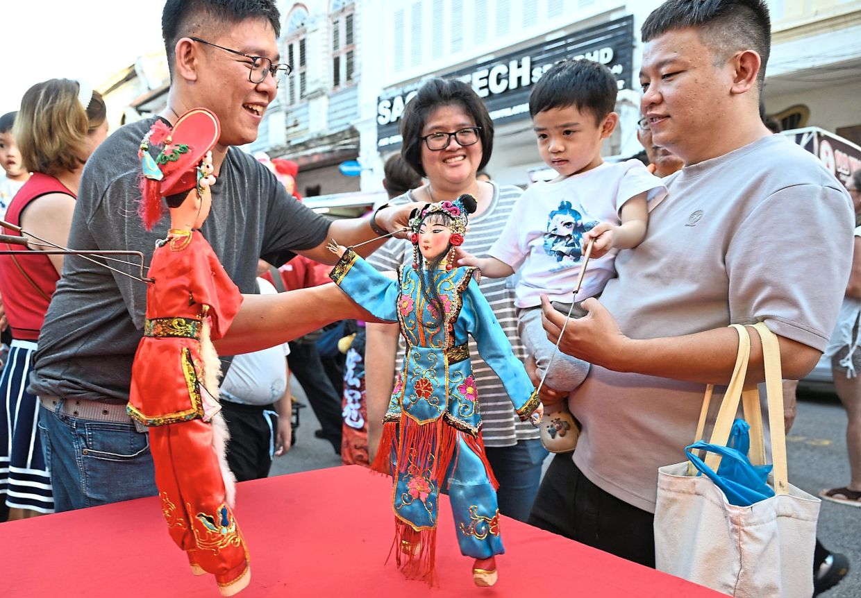 (From left) Puppeteer Low Zhi Kai demonstrating puppet movements to Saw, Zi Wei and Lee (right).