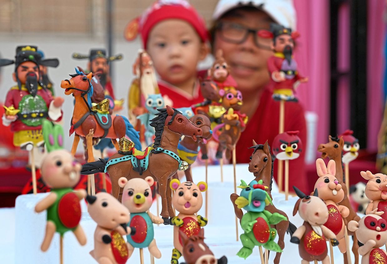 A young visitor captivated by dough figurines on display during the celebration.